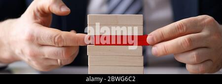 L'uomo gioca a costruire il gioco da tavolo da blocchi di legno Foto Stock