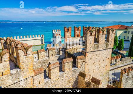 Sirmione, Italia, 11 settembre 2019: Mura di difesa in pietra con merli e mattoni Torre di Castello Scaligero Castello Castello Castello medievale fortezza di Castello, città sul lago di Garda, sfondo blu cielo, Lombardia Foto Stock