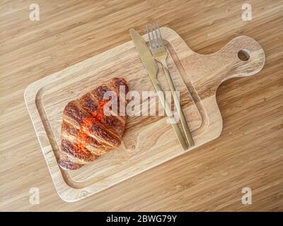 Primo piano di croissant al burro fresco con uovo di sale servire piatto di legno. Foto Stock