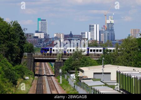 Un treno ferroviario di classe 331 operato dalla Northern Rail passa davanti alla Leeds Skyline Foto Stock