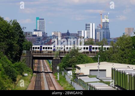 Un treno ferroviario di classe 331 operato dalla Northern Rail passa davanti alla Leeds Skyline Foto Stock