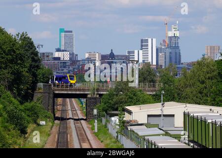 Un treno ferroviario di classe 331 operato dalla Northern Rail passa davanti alla Leeds Skyline Foto Stock