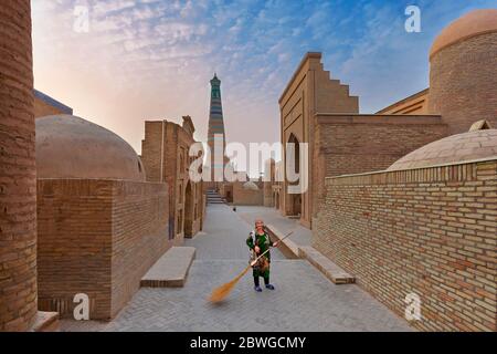 Donna locale che spazzava la strada, a Khiva, Uzbekistan. Foto Stock