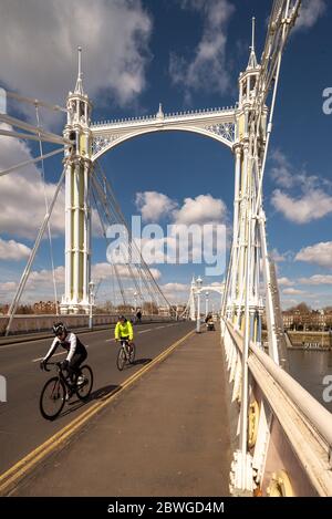 I ciclisti attraversano l'Albert Bridge sul Tamigi, Chelsea, Londra. Un edificio classificato di livello 2 e un ponte stradale unico con caratteristiche d'epoca Foto Stock