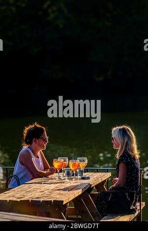 Due Signore che gustano un aparol spritz cocktail nel sole della sera d'estate in una birreria all'aperto nel parco di Battersea Royal Borough of Kensington and Chelsea Foto Stock