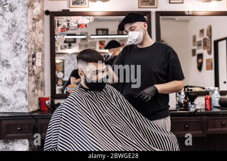 Taglio di capelli in quarantena. Taglio di capelli in maschere dal virus. Capelli e cure sanitarie. Foto Stock
