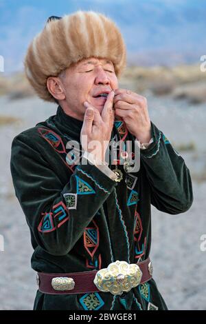 Musicista kirghiso che suona uno strumento musicale tradizionale conosciuto come Timur Komuz, una versione dell'arpa di Jew, in Issyk Kul, Kirghizistan Foto Stock