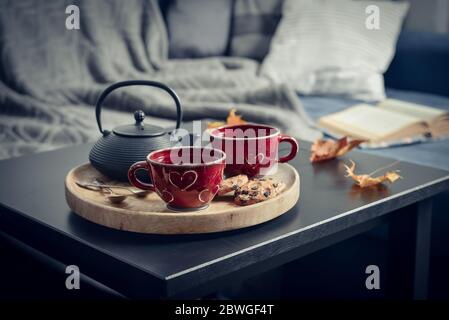 Due tazze di tè su un vassoio da portata sul tavolino da caffè. Colazione sul divano alla luce del sole del mattino. Accogliente concetto di autunno o inverno. Foto Stock