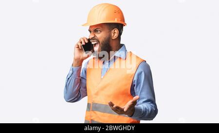 Arrabbiato Builder urlando in Cellphone Standing in Studio, Panorama Foto Stock