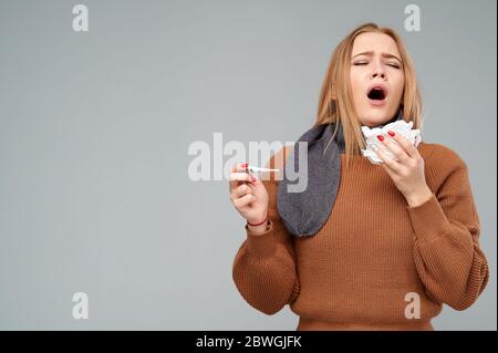 Donna con naso che cola sta per starnutire in un tovagliolo. Virus, malato, concetto di influenza. Isolato Foto Stock