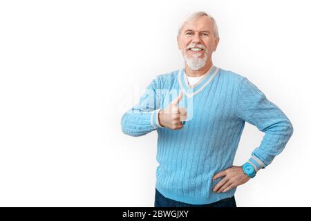 Stile libero. Uomo anziano bearded in maglione in piedi isolato su bianco mostrando pollice su sorridente allegro Foto Stock