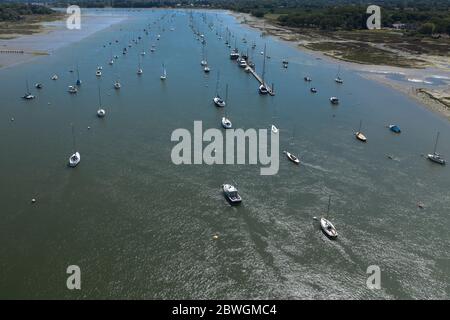 Foto aerea vicino a Itchenor guardando lungo l'estuario con i riflessi sull'acqua e il gran numero di barche ormeggiate. Foto Stock