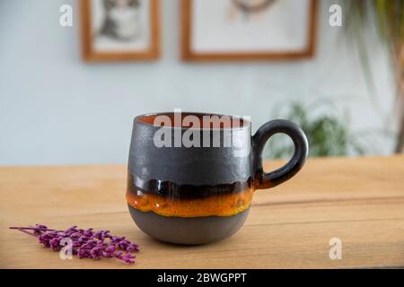 tazzina da caffè in ceramica colorata e fatta a mano su tavolo in legno Foto Stock