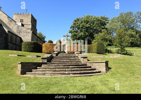 Scalini di pietra che portano ad una statua di Cristo sulla croce nel bellissimo cortile di Kirby Underdale, nello Yorkshire wolds in estate. Foto Stock