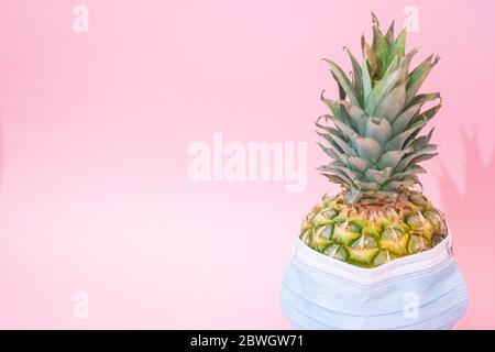 Maschera medica blu contro l'influenza stagionale su un ananas. Concetto minimo Foto Stock