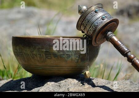 Una ciotola tibetana e una ruota di preghiera Foto Stock
