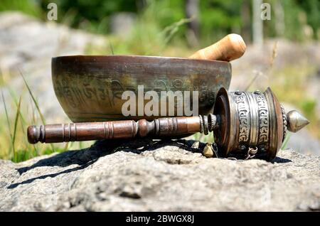 Una ciotola tibetana con una ruota di preghiera Foto Stock
