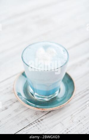 Latte blu matcha in vetro su sfondo bianco di legno Foto Stock