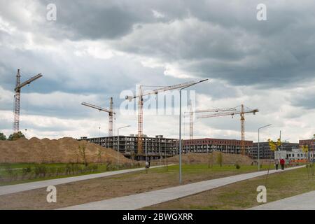 Gru di costruzione vicino agli edifici non finiti. Costruzione e sviluppo di nuovi distretti Foto Stock