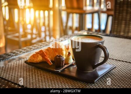 Latte di caffè con croissant e pasticceria sul tavolo nella caffetteria Foto Stock