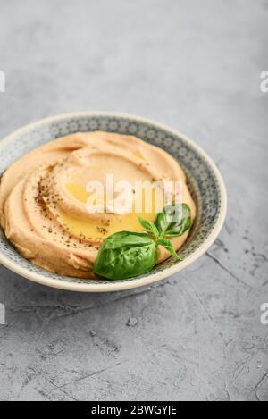 Ciotole con diversi tipi di hummus su sfondo grigio, primo piano Foto Stock