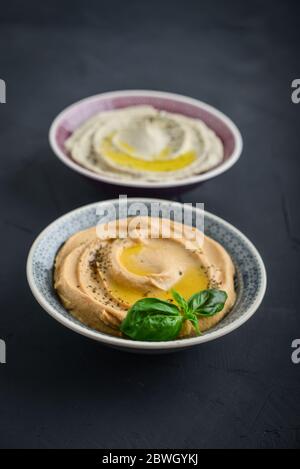 Ciotole con diversi tipi di hummus su fondo nero closeup Foto Stock