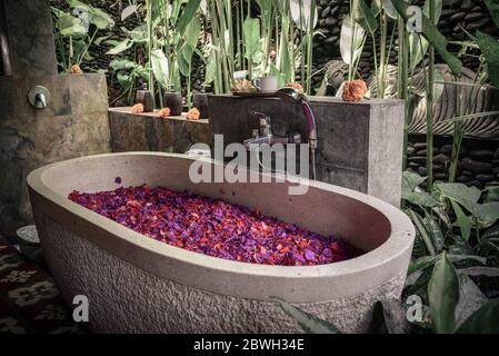 Vasca da bagno con petali di fiori - parte tradizionale di trattamento termale balinese Foto Stock