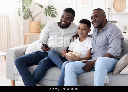 Allegro nonno africano, padre e figlio che si rilassano insieme in soggiorno Foto Stock