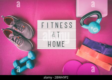Segno di idoneità a casa con tappetino di yoga rosa, scarpe da corsa, peso di kettlebell e manubri bande di resistenza e slider per pilates classe online. Esercizio in interni per le donne. Foto Stock