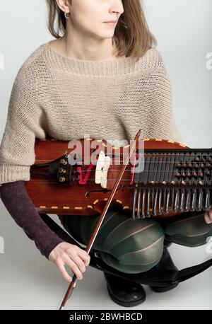 Giovane donna che gioca una nyckelharpa tradizionale in un primo piano sul prua in mano come lei gioca in un primo piano su un ritratto ritagliato Foto Stock
