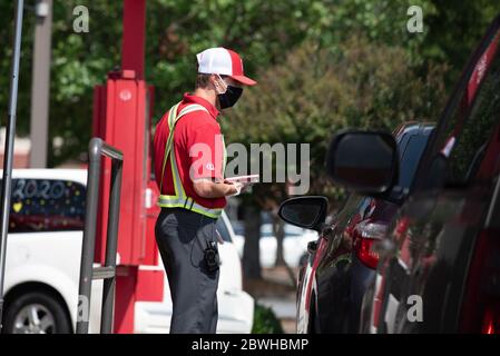 Roswell, Georgia, Stati Uniti. 1 Giugno 2020. Il dipendente mascherato e malvagio del ristorante Chick-fil-A prende ordine da un cliente drive-through utilizzando tablet e carta di credito, riducendo al minimo il rischio di diffusione del virus Covid-19. Credit: Robin Rayne/ZUMA Wire/Alamy Live News Foto Stock