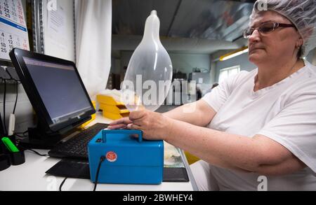 Sarstedt, Germania. 20 Maggio 2020. Un dipendente sottopone un preservativo prodotto di recente a un controllo di qualità nello stabilimento CPR GmbH. Ogni singolo preservativo viene controllato elettronicamente man mano che la produzione procede. Secondo il boss dell'azienda Kesselring, CPR è uno dei maggiori produttori di preservativi in Europa. Credit: Julian Stratenschulte/dpa/Alamy Live News Foto Stock