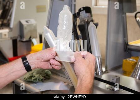 Sarstedt, Germania. 20 Maggio 2020. Un dipendente tira i preservativi su un dispositivo metallico mentre controlla un campione casuale durante il controllo di qualità presso l'impianto CPR GmbH. Man mano che la produzione procede, ogni singolo preservativo viene controllato elettronicamente. Secondo il boss dell'azienda Kesselring, CPR è uno dei maggiori produttori di preservativi in Europa. Credit: Julian Stratenschulte/dpa/Alamy Live News Foto Stock