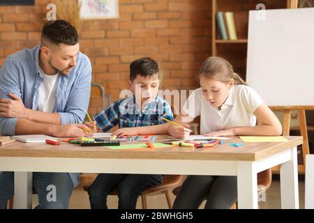 Insegnante di disegno che dà lezioni facoltative a scuola Foto Stock