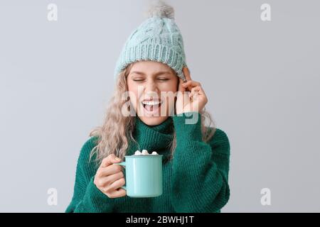 Bella giovane donna con una tazza di cioccolato caldo su sfondo grigio Foto Stock