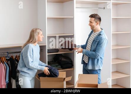Giovane coppia disimballare i vestiti nel loro nuovo appartamento in giorno di movimento Foto Stock