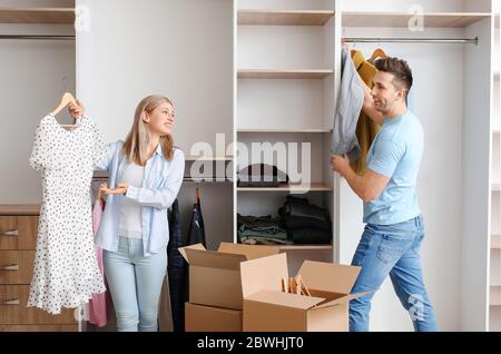 Giovane coppia disimballare i vestiti nel loro nuovo appartamento in giorno di movimento Foto Stock
