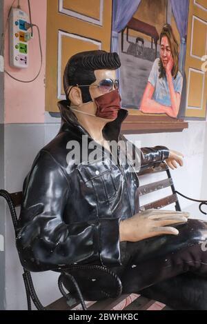 Durante la pandemia di Covid-19 (nCorona) nel 2020, una statua seduta di Elvis Presley di fronte ad un caffè a Bangkok, Thailandia, indossa una maschera facciale Foto Stock