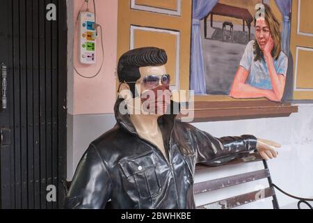 Durante la pandemia di Covid-19 (nCorona) nel 2020, una statua seduta di Elvis Presley di fronte ad un caffè a Bangkok, Thailandia, indossa una maschera facciale Foto Stock