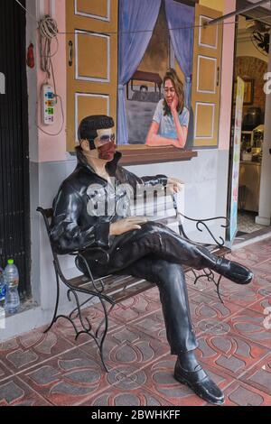 Durante la pandemia di Covid-19 (nCorona) nel 2020, una statua seduta di Elvis Presley di fronte ad un caffè a Bangkok, Thailandia, indossa una maschera facciale Foto Stock