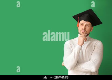 Uomo premuroso in cappello di laurea su sfondo colorato Foto Stock