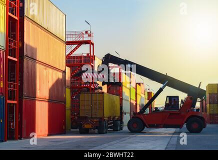 Raggiungere il raccoglitore scaricare il contenitore dal carrello nei cantieri di container, operazioni logistiche. Foto Stock