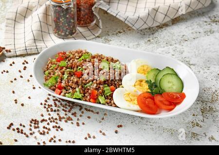 Piatto con gustoso grano saraceno, uova e verdure sul tavolo Foto Stock