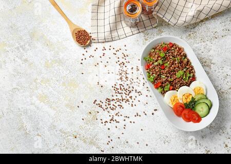 Piatto con gustoso grano saraceno, uova e verdure sul tavolo Foto Stock