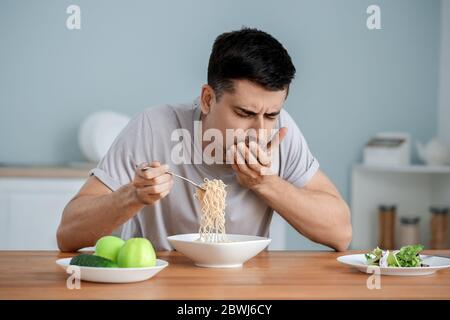 Giovane con anoressia che mangia noodle a casa Foto Stock