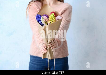 Donna con bellissimi fiori di giacinto su sfondo chiaro, closeup Foto Stock