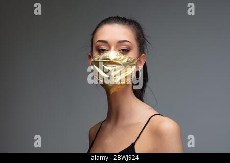 donna hughty che indossa una maschera dorata - concetto di maschere chirurgiche aumento di prezzo quando sono obbligatori e estremamente rari come sono necessari per mi Foto Stock