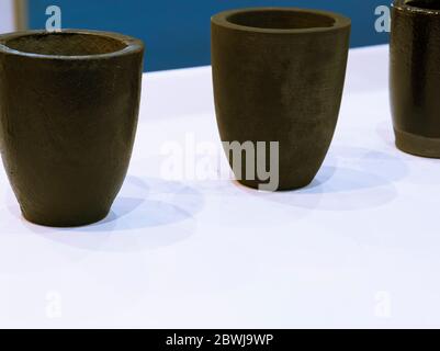Il piccolo nero crogiolo ceramico per trasferire il metallo fuso nello stampo ; ingegneria industriale sullo sfondo di apparecchiature Foto Stock