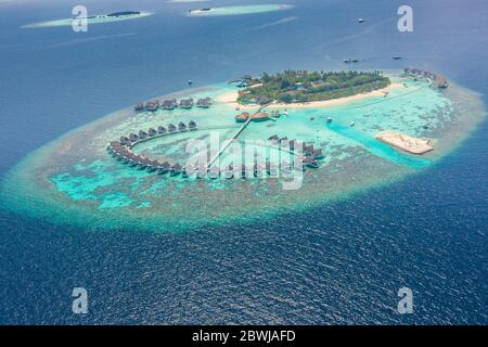 Isola tropicale alle Maldive. Resort di lusso con vista aerea, ville sull'acqua e bungalow su un mare blu e una laguna mozzafiato. Vacanza estiva di lusso Foto Stock