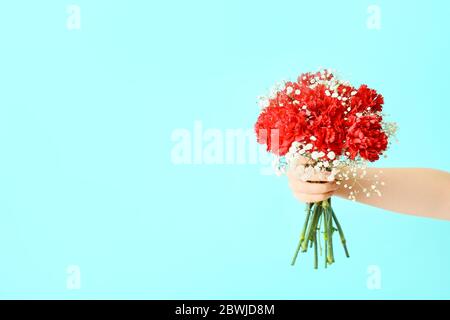 Mano femminile con bouquet di fiori belli su sfondo colorato Foto Stock